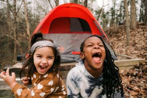 Two young girls laughing outside of a tent