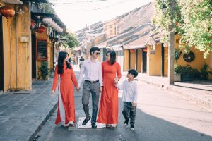 A family of four walking down the street holding hands.